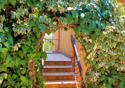 Entrée latérale avec une arche en verdure menant à un des appartements des Terrasses de Figanières