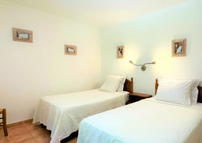 Chambre avec deux lits simples aux draps blancs et une chaise dans le coin