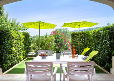 Terrasse avec partie couverte, table à manger et jardin avec deux transats