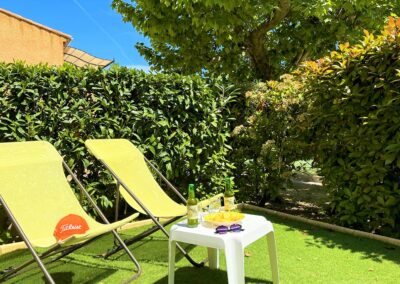 Terrasse au rez-de-chaussée, entourée par la nature, avec deux transats, une table basse et un apéritif prêt à servir
