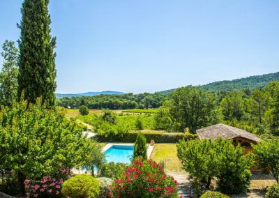 Vue depuis la résidence des Terrasses de Figanières sur la piscine, le jardin, les vignobles et les collines verdoyantes environnantes