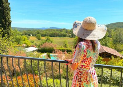 Femme avec chapeau en train de regarder la vue dégagée sur les vignes depuis sa terrasse